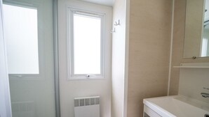 A bathroom with a white sink, a mirror above it, a radiator below, and a window with a view. - Holiday Home in Amstelveen With Terrace (Amstelveen)