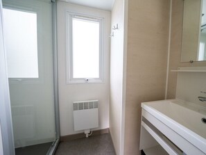A bathroom with a white sink, a mirror above it, a radiator below, and a window with a view. - Holiday Home in Amstelveen With Terrace (Amstelveen)