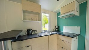 A compact kitchen with a black countertop, beige cabinets, a window, and a teal accent wall. - Holiday Home in Amstelveen With Terrace (Amstelveen)