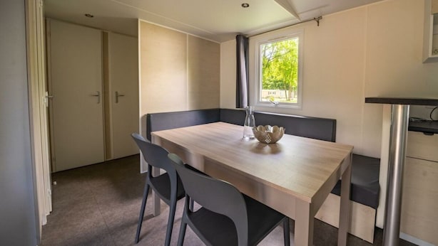 A dining area with a wooden table, two chairs, a vase, and a window with a view of trees. - Holiday Home in Amstelveen With Terrace (Amstelveen)