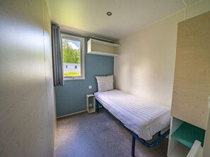 A small, single-bed room with a window, a built-in shelf, and a door. - Holiday Home in Amstelveen With Terrace (Amstelveen)