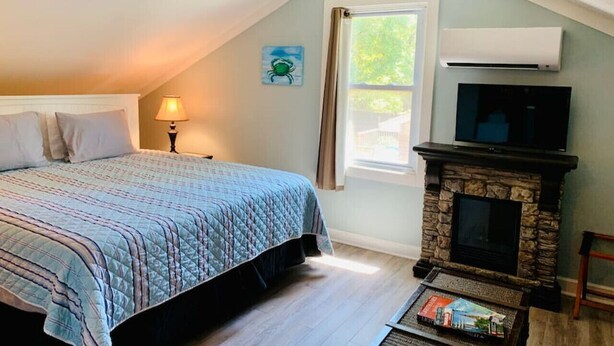 Une chambre à coucher avec un lit, une table de chevet, une lampe, une cheminée et une fenêtre.