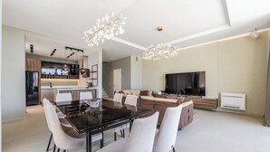 Ein modernes Wohnzimmer mit Essbereich, Küche und Fernseher.