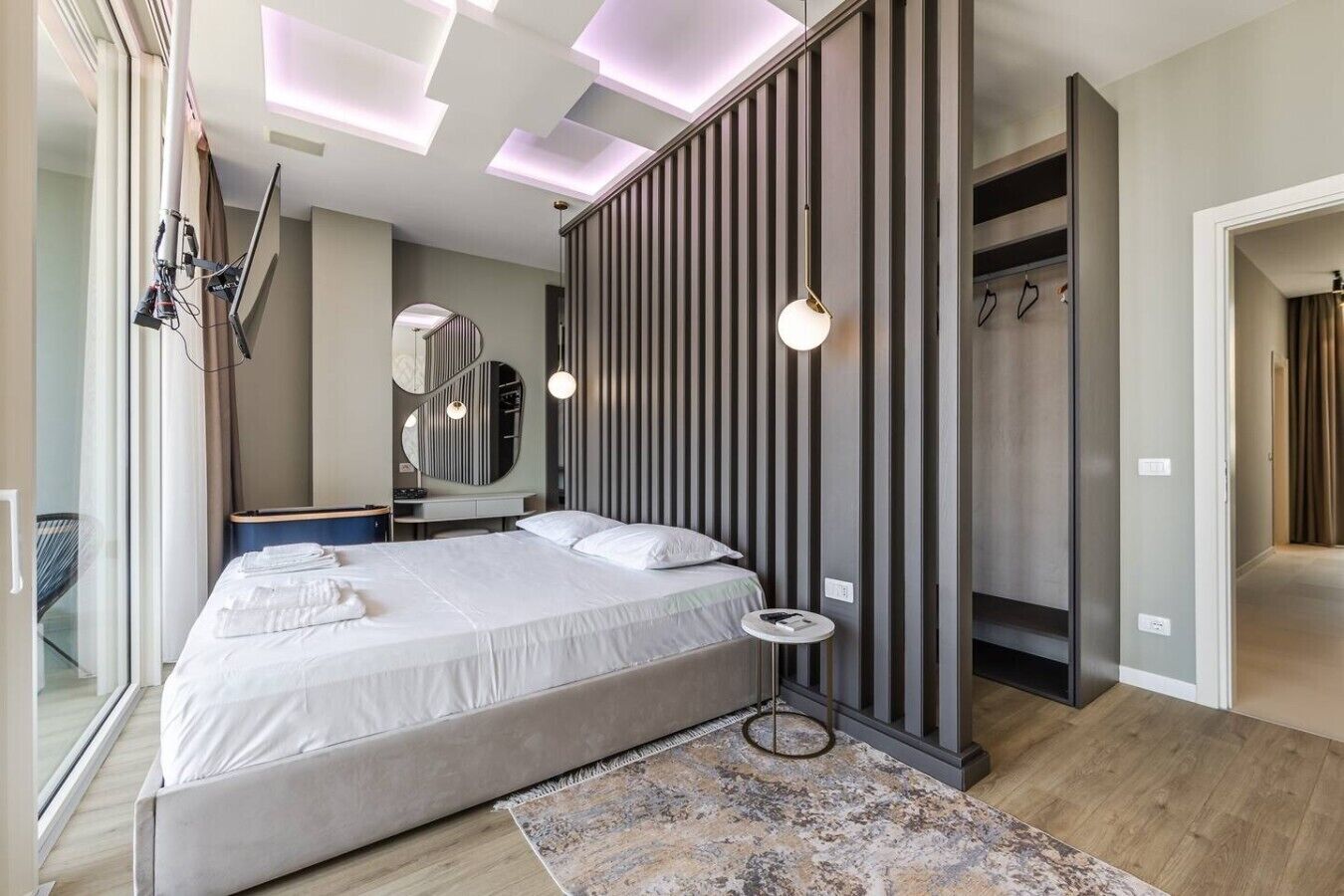 Un dormitorio moderno con una cama grande, un espejo, un armario y una lámpara en el techo.