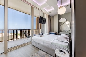 Une chambre d’hôtel moderne avec un balcon, un lit, une télévision, un miroir et une petite table.