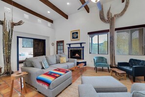 A living room with a fireplace, sofas, a coffee table, and a large window.