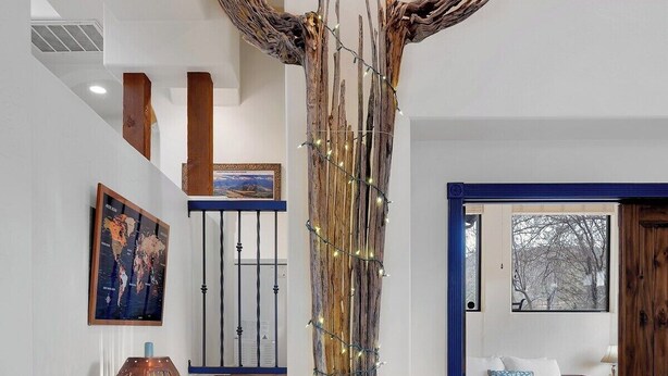 Un salon avec une grande sculpture en forme d’arbre, une lampe, une carte et un lit.
