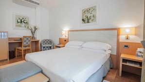 Een hotelkamer met een bed, bureau, stoel, nachtkastjes en kunst aan de muren.