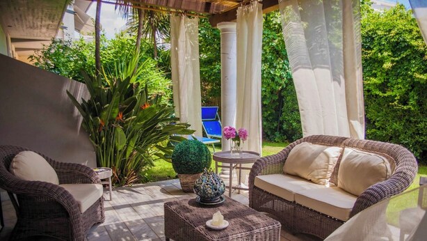 Een terras buiten met wicker meubels, een kleine tafel en een potplant.
