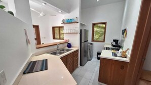 Una cocina pequeña con lavamanos, refrigerador y una pequeña zona de encimera.