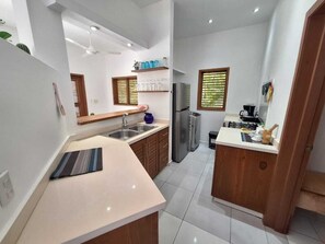 Eine kleine Küche mit Spüle, Kühlschrank und einer Arbeitsfläche.