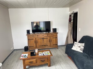 Ein Wohnzimmer mit Flachbildfernseher, Holzschrank und einer Couch mit Kissen.