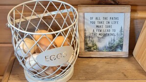 A metal basket labeled 'EGGS' on a wooden shelf, next to a framed inspirational quote. - Gorgeous tiny home with mountain views in peaceful Candler (Candler)