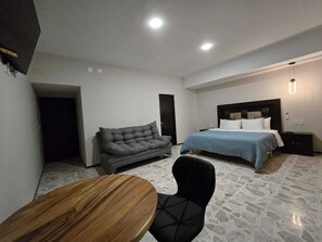 Een hotelkamer met een bed, een slaapbank, een eettafel en een stoel.