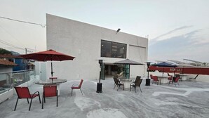Una terraza en la azotea con mobiliario exterior, un edificio con amplios ventanales y paneles solares.
