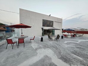 Una terrassa al terrat amb seients a l'aire lliure, un edifici amb finestrals grans i panells solars.