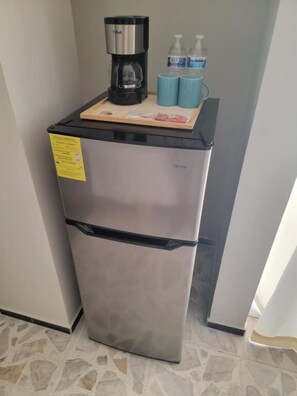 A stainless steel refrigerator with a coffee maker, two blue cups, and a small tray with items. - Suites & Lofts Olivier (Uruapan)
