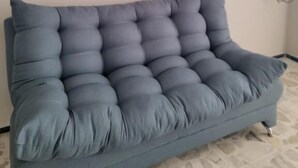Una habitación con un sofá gris, un televisor de pantalla plana montado y un enchufe en la pared.