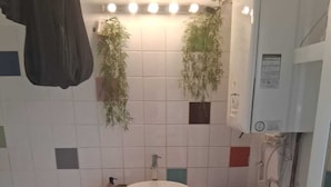 A small bathroom with a white sink, a mirror, a towel rack, a small stool, and a plant. - House Cocoon paradise in the North direct metro Lille ideal for groups! (Roubaix)