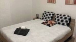 A single bed with a white mattress and a wooden frame, a bedside table with a lamp, and two wall-mounted artworks. - House Cocoon paradise in the North direct metro Lille ideal for groups! (Roubaix)