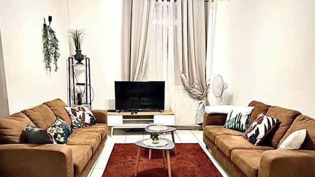 A living room with two sofas, a TV, a small table, and a red rug. - House Cocoon paradise in the North direct metro Lille ideal for groups! (Roubaix)