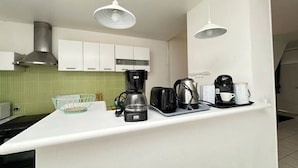 A kitchen with white cabinets, a green tiled backsplash, a coffee maker, and a kettle on the counter. - House Cocoon paradise in the North direct metro Lille ideal for groups! (Roubaix)