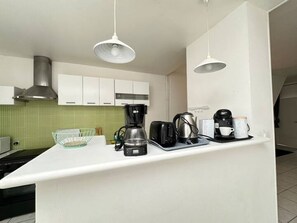 A kitchen with white cabinets, a green tiled backsplash, a coffee maker, and a kettle on the counter. - House Cocoon paradise in the North direct metro Lille ideal for groups! (Roubaix)