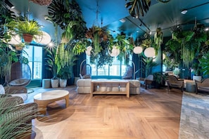 A spacious living room with a wooden floor, a sofa, a coffee table, and hanging plants. - Brand New Apt 1 Bed 4 Guest Bay & Brickell View (Miami)
