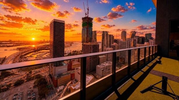 Vista urbana do alto de uma varanda ao pôr do sol.
