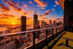 Une vue sur la ville depuis le balcon d’un immeuble de grande hauteur, au coucher du soleil.