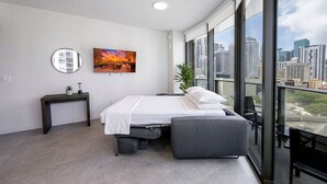 Quarto moderno com cama, mesa de cabeceira e uma grande janela com vista para a cidade.