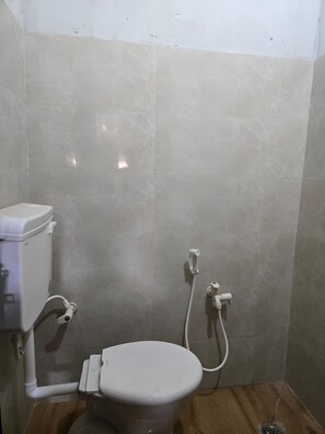 Ein kleines, sauberes Badezimmer mit Toilette, Duschbrause und Bidet.