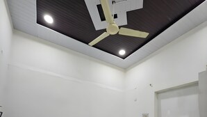 Een slaapkamer met een bed, een plafondventilator, een raam en een witte muur.