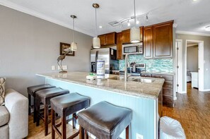 A kitchen with a large island, wooden cabinets, stainless steel appliances, and pendant lighting. - 2 Pools, Hot Tub, Dogs Free, Right on the Beach! (Galveston)