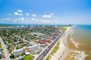 An aerial view of a coastal city with a beachfront, roads, and residential areas. - 2 Pools, Hot Tub, Dogs Free, Right on the Beach! (Galveston)