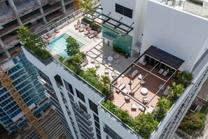 A rooftop pool area with lounge chairs, a small pool, and a seating area with tables and chairs. - New Boutique Studio | 2 Guests | Downtown Miami (Miami)