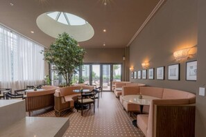 A modern interior with a central tree, seating areas, and framed pictures on the walls. - New Boutique Studio | 2 Guests | Downtown Miami (Miami)