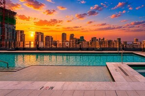 Ein Pool auf dem Dach mit Blick auf die Stadt bei Sonnenuntergang, ein 'NO TRESPASSING'-Schild und ein 'NO TRESPASSING'-Symbol am Poolrand.