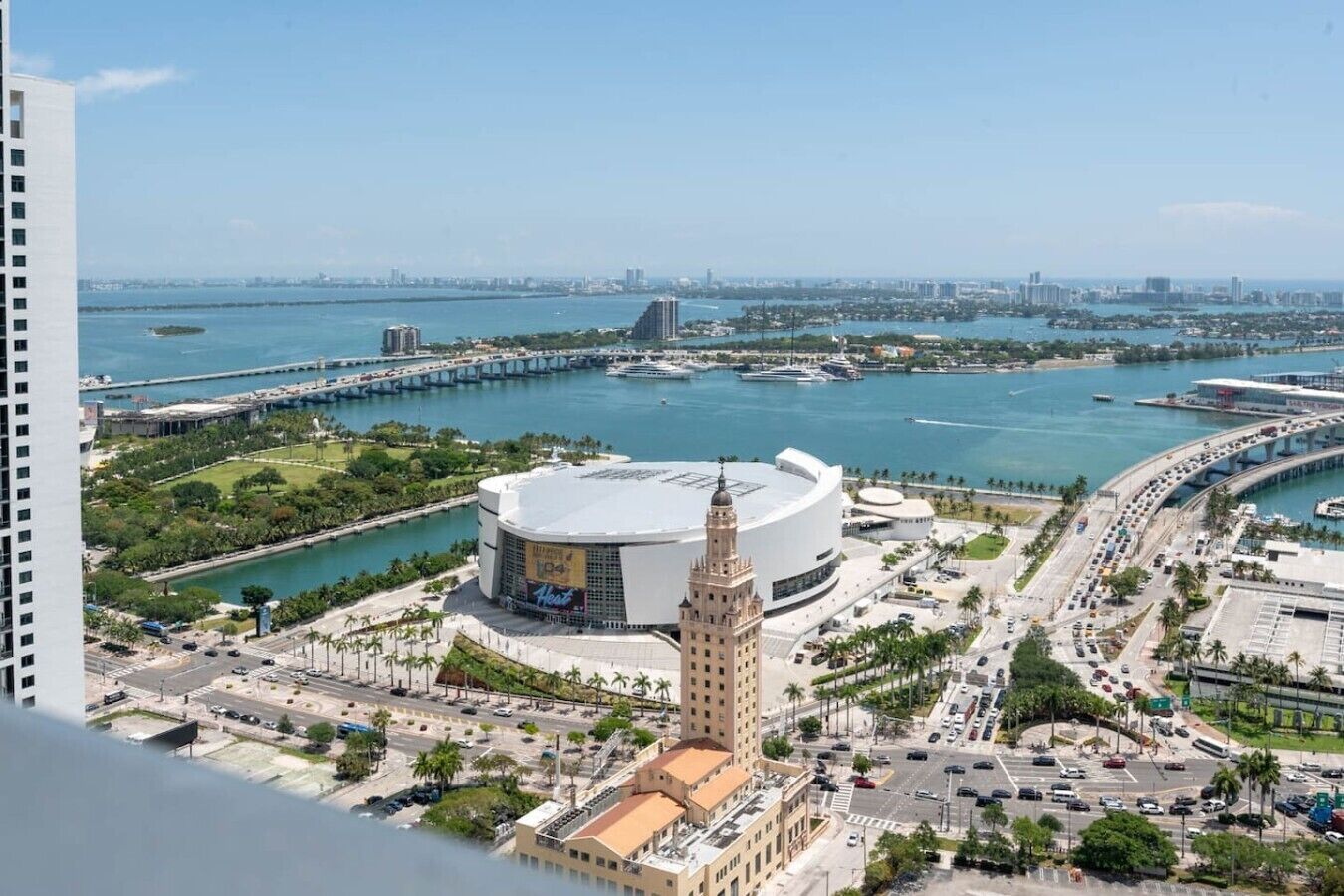A cityscape with a prominent round building, a tall tower, and a waterfront area.