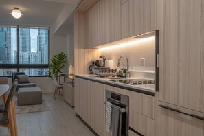 Eine moderne Küche mit integrierten Geräten, ein Essbereich mit Blick auf die Stadt und ein großes Fenster.