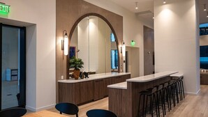 A modern reception area with a wooden reception desk, a large mirror, and a seating area with bar stools. - FREE Parking • Corner Unit • Bay & Brickell Views (Miami)
