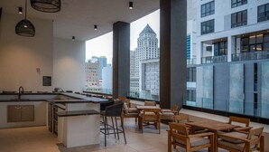 A modern kitchen with a bar area, large windows with city views, and a seating area with wooden furniture. - FREE Parking • Corner Unit • Bay & Brickell Views (Miami)