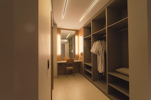 A hotel room with a desk, chair, and a walk-in closet with shelves.