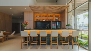 A modern bar area with wooden chairs, a counter, and shelves with bottles. - MANTRA HOTEL (Vera)