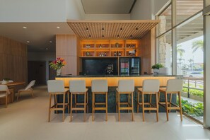 Un espace bar moderne avec des chaises en bois, un comptoir et des étagÚres remplies de bouteilles.
