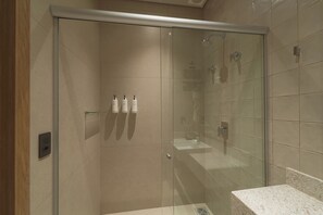 Une salle de bain moderne dotĂ©e dâune douche Ă parois de verre, dâun lavabo en marbre et dâun distributeur de serviettes fixĂ© au mur.