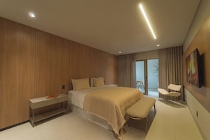 A modern bedroom with a large bed, a bench, a chair, and a painting on the wall.