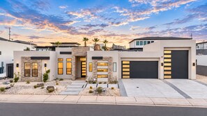 A modern two-story house with a stone facade, large windows, and a garage. - Pecan Valley Oasis | Private Backyard Paradise (Hurricane)