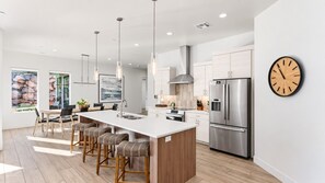 A modern kitchen with a central island, stainless steel appliances, and pendant lighting. - Pecan Valley Oasis | Private Backyard Paradise (Hurricane)