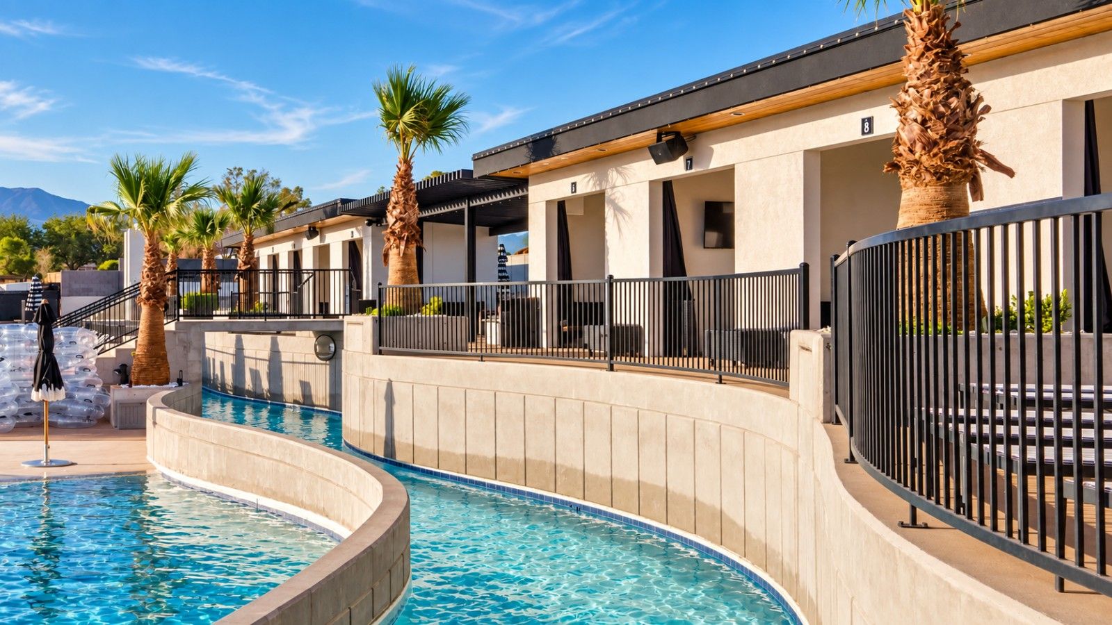 A pool area with a curved design, palm trees, and a building with balconies.